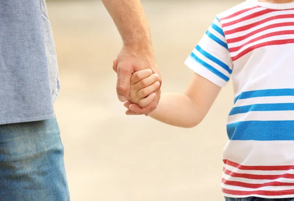 Мальчик держит отца за руку на улице — стоковое фото