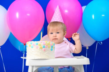 Lezzetli pasta sandalye ve dekorasyonu için doğum günü partisi arka plan üzerinde oturan ile sevimli küçük kız