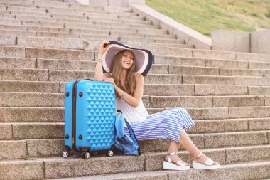 Güzel genç turist merdivenlerde oturan çanta