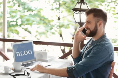 Kafede telefonda konuşurken laptop ile genç blogger