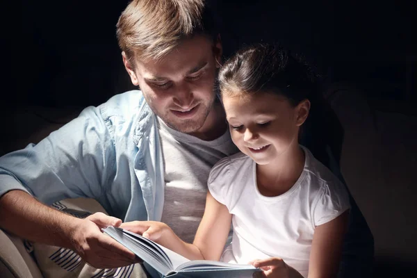 Jovem e sua filhinha lendo livro tarde da noite — Fotografia de Stock