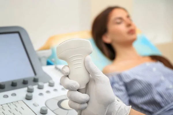 Médico sosteniendo equipo de ultrasonido y paciente borroso en el fondo —  Fotos de Stock