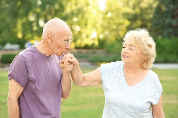 Anciano besándose la mano de señora mayor en el parque — Foto de Stock