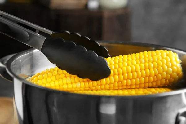 Tongs taking out corn cob — Stock Photo, Image