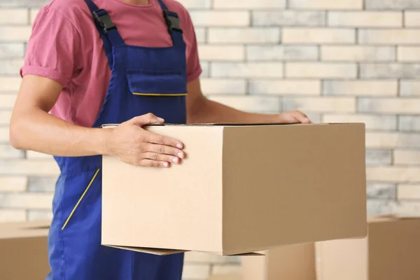 Delivery man holding box, indoors — Stock Photo, Image