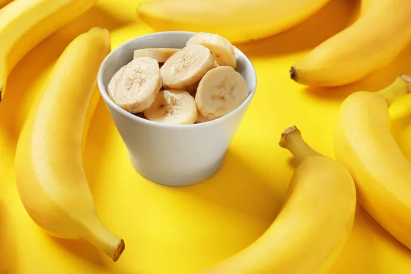 Bananas and bowl with slices — Stock Photo, Image