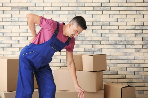 Hombre que sufre de dolor de espalda mientras mueve cajas, en el interior — Foto de Stock