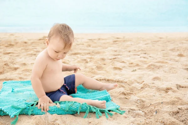 Roztomilý chlapec seděl na pláži — Stock fotografie