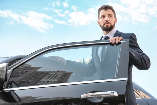 Handsome man in suit getting in car — Stock Photo, Image