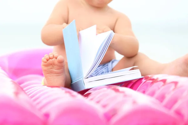 Cute baby boy sitting on inflatable mattress at beach — Stock Photo, Image