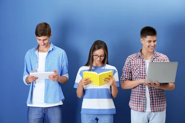 Adolescentes com gadgets e livro sobre fundo de cor — Fotografia de Stock