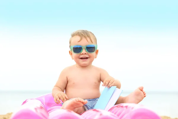 Lindo bebé niño sentado en colchón inflable en la playa —  Fotos de Stock