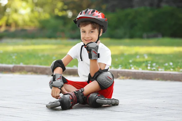 Lindo chico en patines sentado en el parque — Foto de Stock