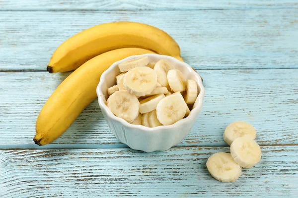 Bananas and bowl with slices — Stock Photo, Image