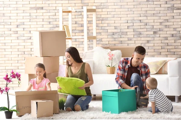 Gelukkige familie uitpakken karton vakken in de kamer in het nieuwe huis — Stockfoto