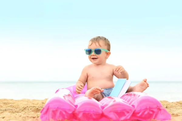 Lindo bebé niño sentado en colchón inflable en la playa — Foto de Stock