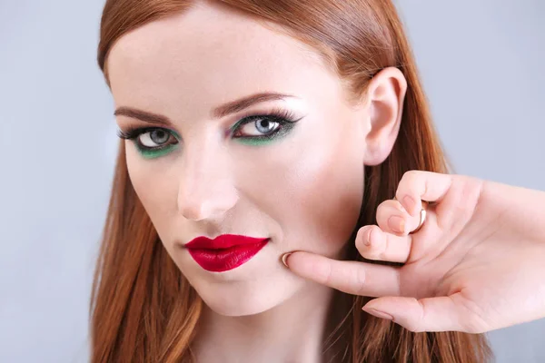 美丽的红头发的女人与明亮的绿色化妆在光背景 — 图库照片