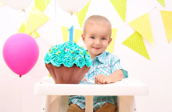 Bonito menino com bolo de aniversário no fundo brilhante — Fotografia de Stock