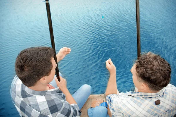 Dos hombres pescando desde el muelle en el río — Foto de Stock