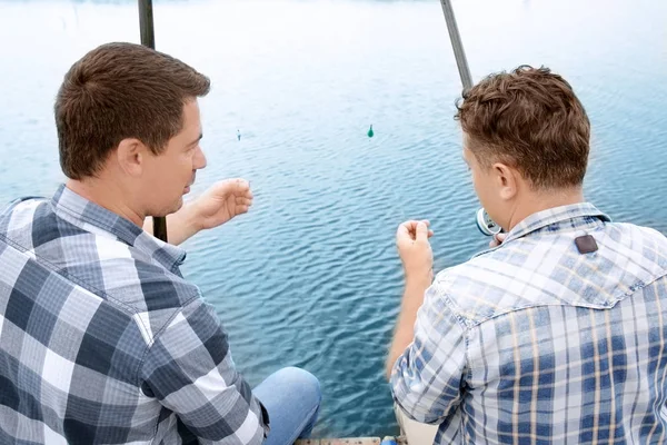 Dois homens pescando do cais no rio — Fotografia de Stock