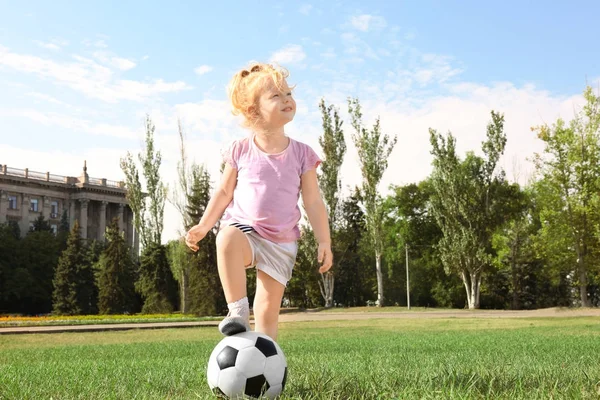Menina bonito com bola de futebol no gramado — Fotografia de Stock