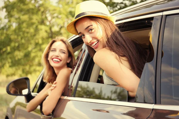 Beautiful young women looking out of open car window — Stock Photo, Image