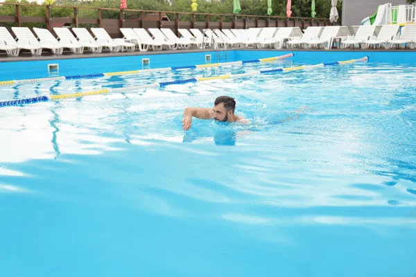 Schöner junger Mann schwimmt im Pool, im Freien — Stockfoto