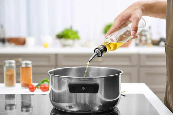Man pouring cooking oil into saucepan — Stock Photo, Image