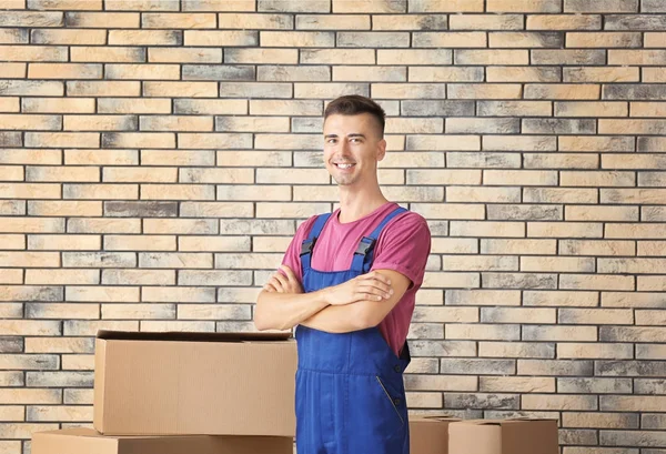 Entrega hombre de pie cerca de cajas de cartón, en el interior — Foto de Stock