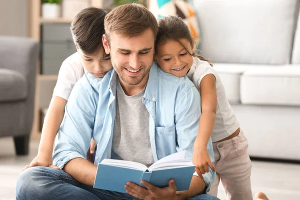 Jonge man en zijn lieve kinderen lezen boek thuis — Stockfoto