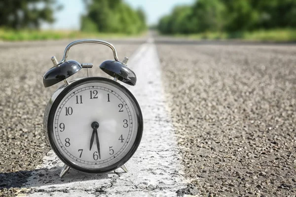 Alarm clock on rural road — Stock Photo, Image