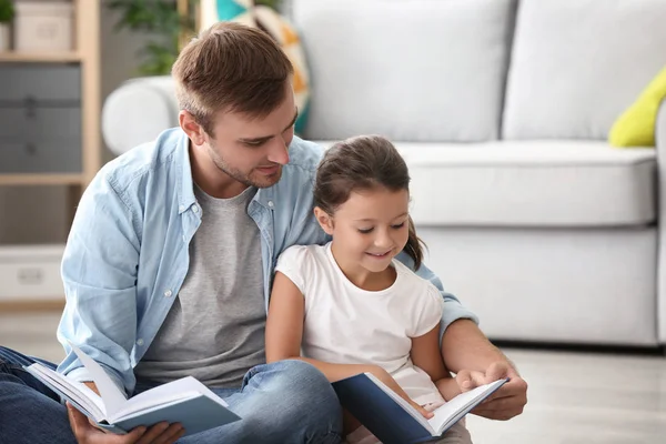 若い男と彼の小さな娘の読書本を自宅 — ストック写真