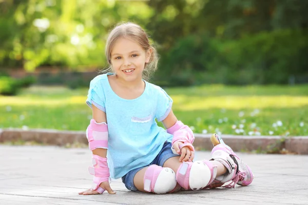 Vrolijk meisje op rolschaatsen zitten in park — Stockfoto