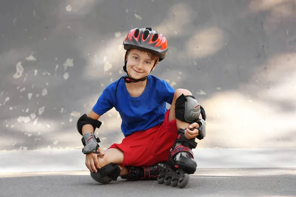 Lindo chico en rodillos sentado en skate park — Foto de Stock