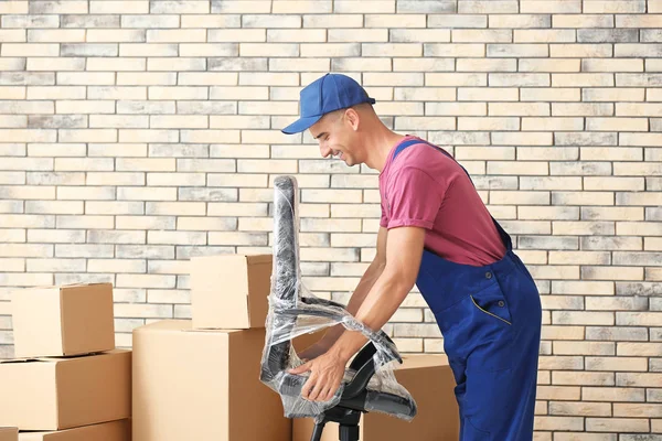 Entrega homem segurando cadeira, dentro de casa — Fotografia de Stock