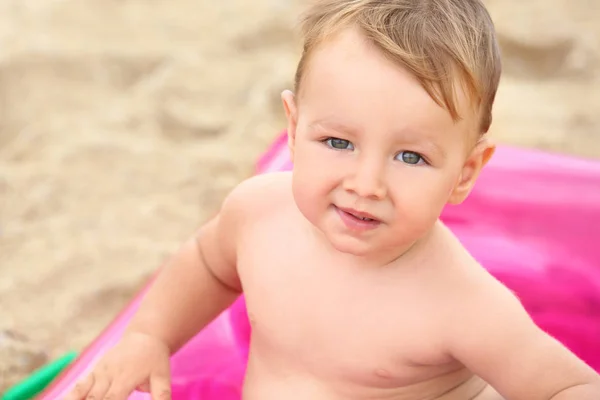 Ładny chłopczyk siedzi na nadmuchiwany materac na plaży — Zdjęcie stockowe