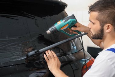 Worker tinting car window in shop clipart