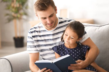 Genç adam ve onun küçük kızı okuma kitabı evde