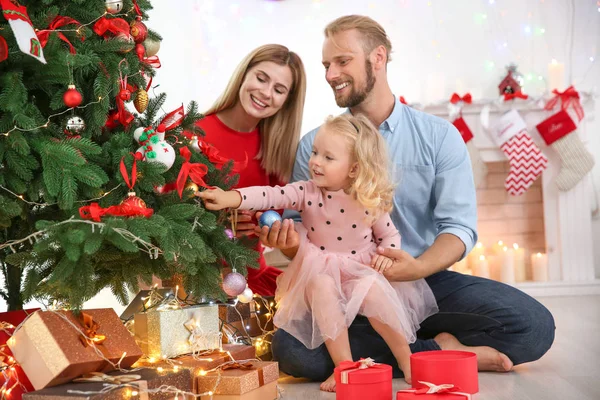 Casal feliz com pequena filha decorando árvore de Natal em casa — Fotografia de Stock