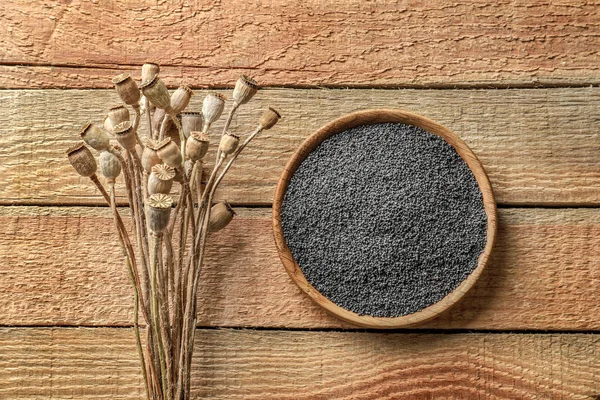 Bouquet de têtes de pavot et assiette avec graines sur table en bois — Photo