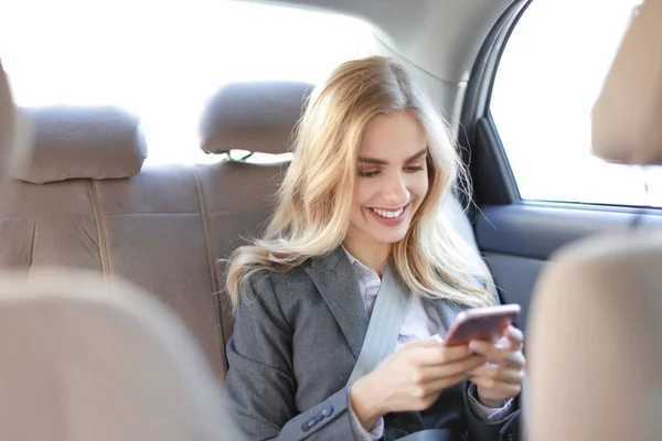 Jovem empresária com telefone celular no carro — Fotografia de Stock