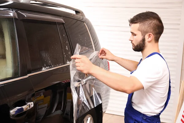 Worker tinting car window in shop — Stock Photo, Image
