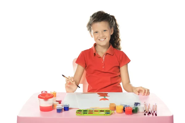 Маленькая милая девочка рисует за столом на белом фоне — стоковое фото