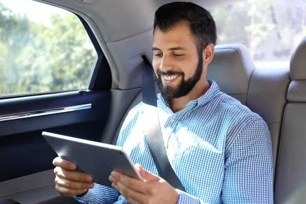 Bel homme avec tablette sur le siège arrière de la voiture — Photo