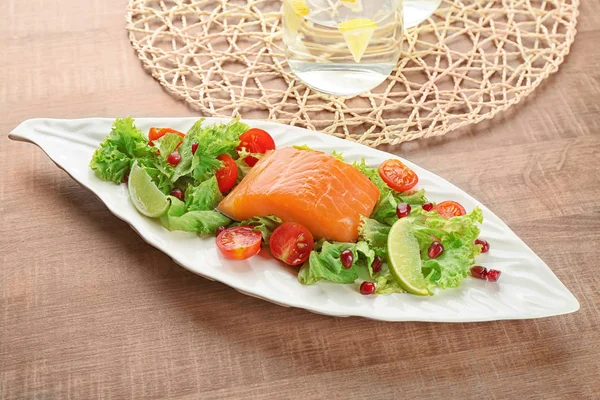 Placa con deliciosa ensalada de salmón en la mesa —  Fotos de Stock