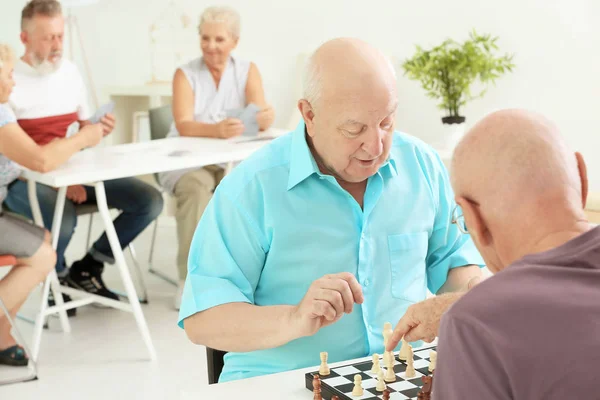 Elderly men playing chess at home — Stock Photo, Image