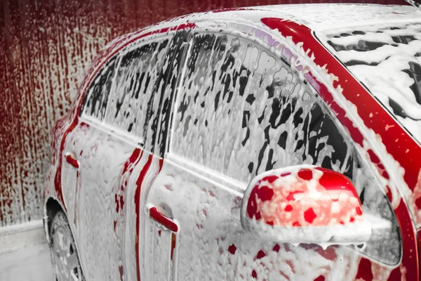 Automóvil rojo en espuma en el lavado de coches — Foto de Stock