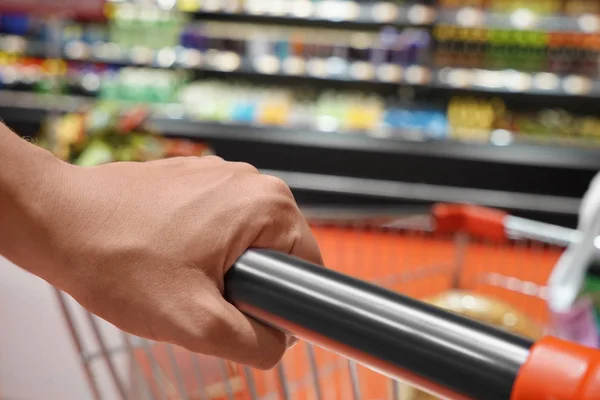 Jonge vrouw met trolley kiezen van producten — Stockfoto