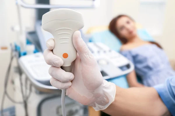 Doctor holding ultrasound equipment and blurred patient on background — Stock Photo, Image