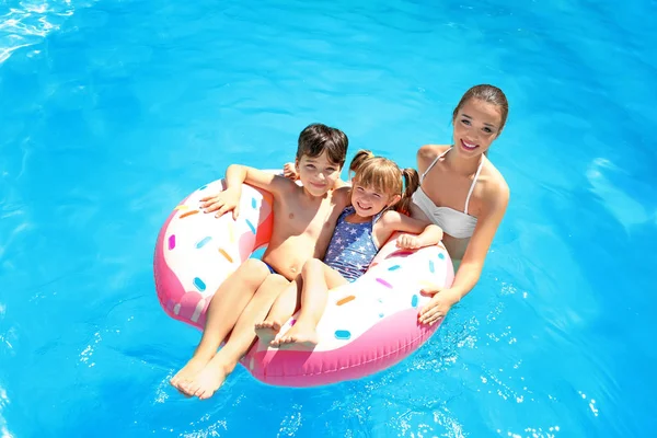 Jeune femme et ses enfants avec beignet gonflable dans la piscine — Photo